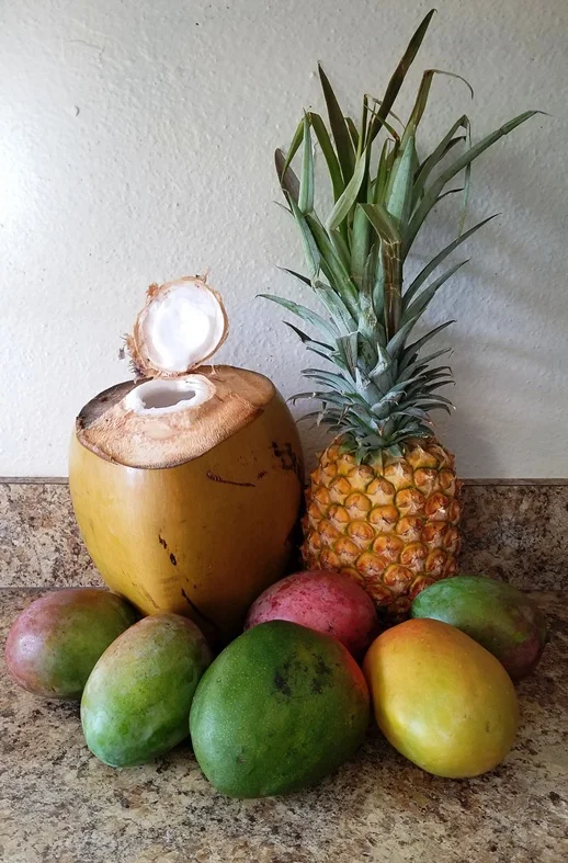 A fresh coconut, a pineapple, and several mangoes, all gathered to make the mango ʻotai.