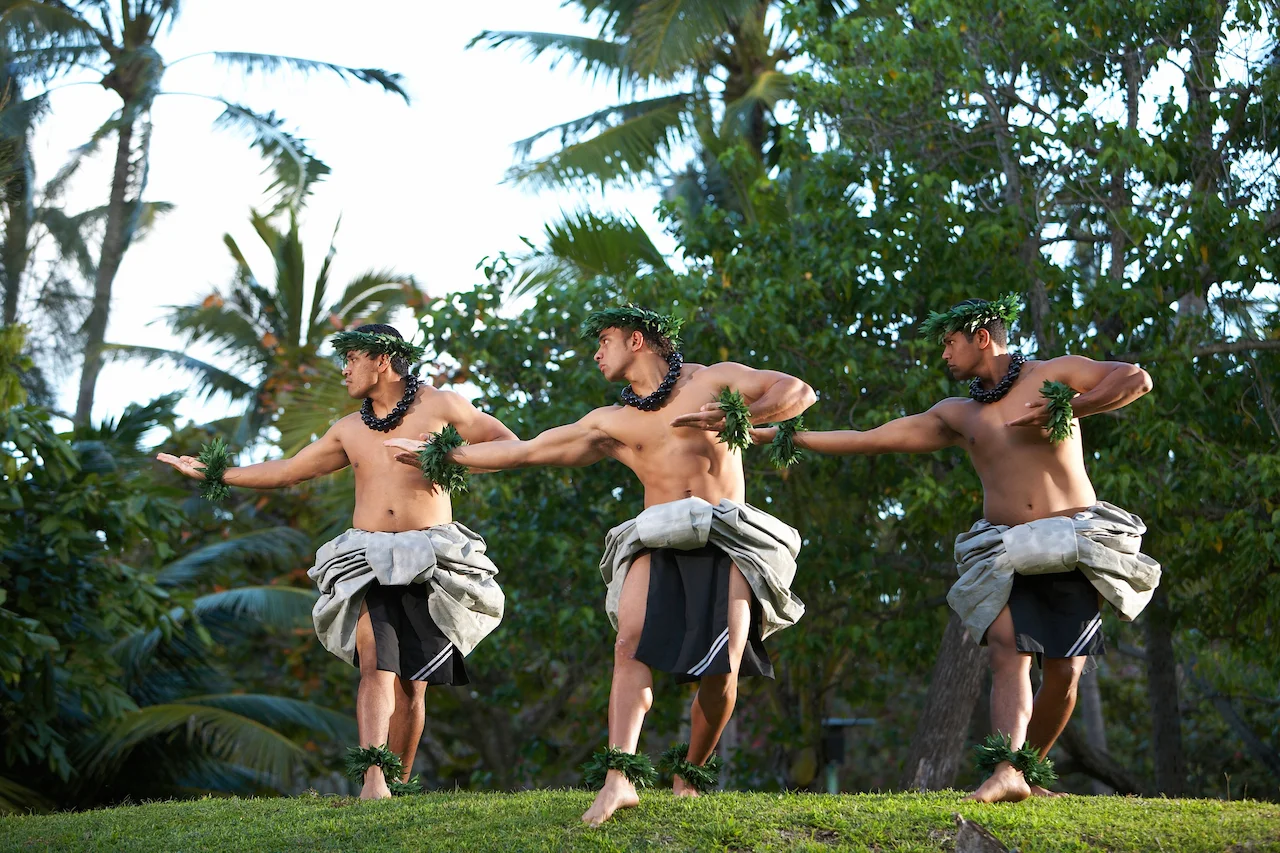 Men in traditional attire performing hula kahiko at the lūʻau.