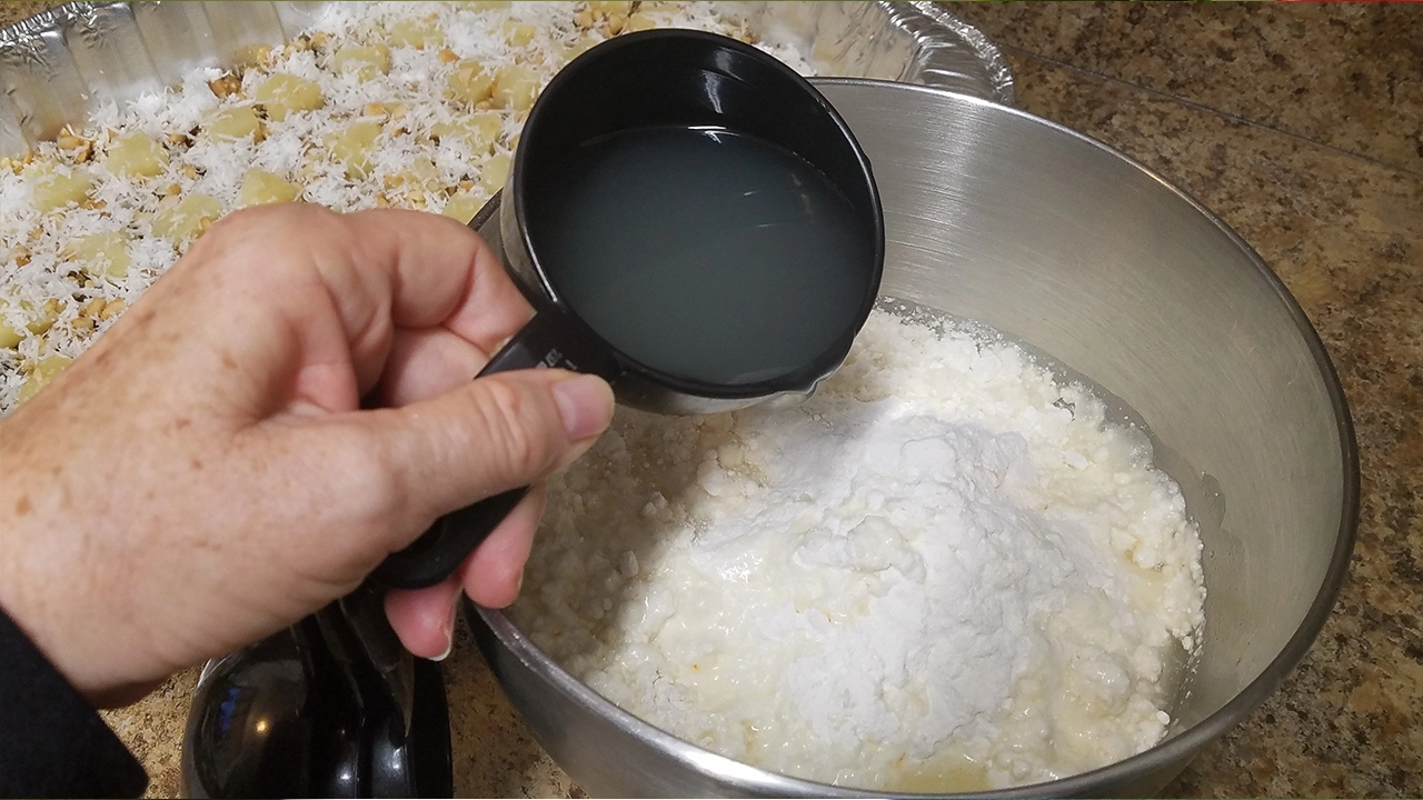 Using a measuring cup to pour juice into mix.