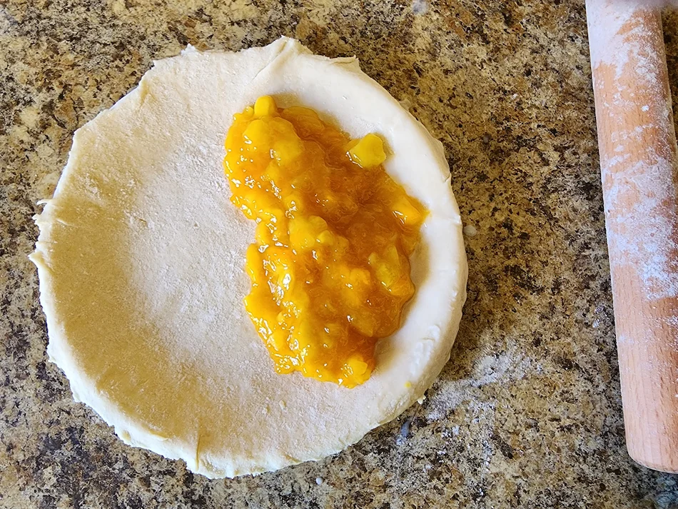 The pie crust with the pineapple filling added to one half