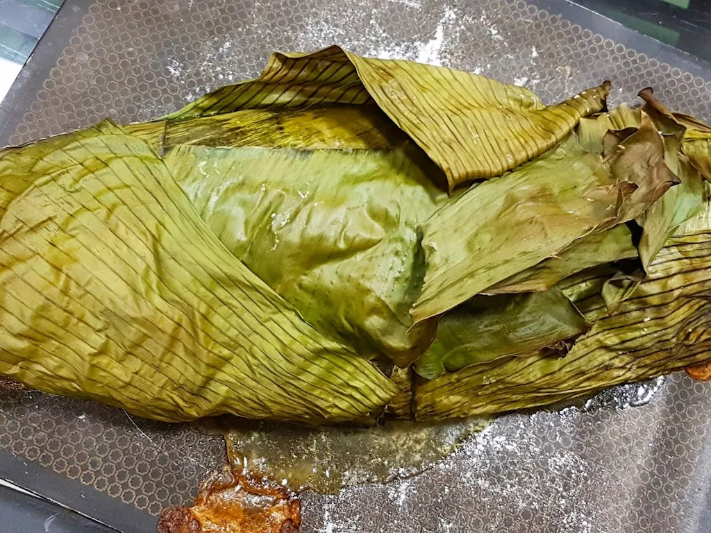 Large kampachi fish wrapped in leaves for cooking.