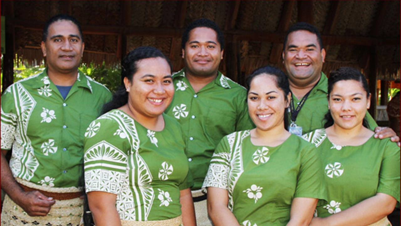 Six Tongan employees of the Polynesian Cultural Center wearing matching green and white floral shirts