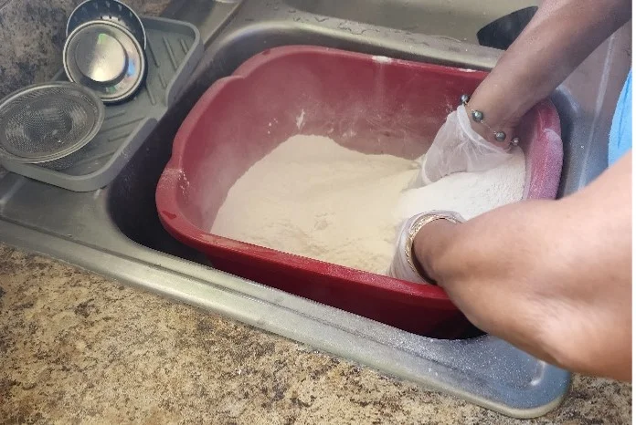 Mixing the ingredients in a large bin to make Tahitian coconut bread 