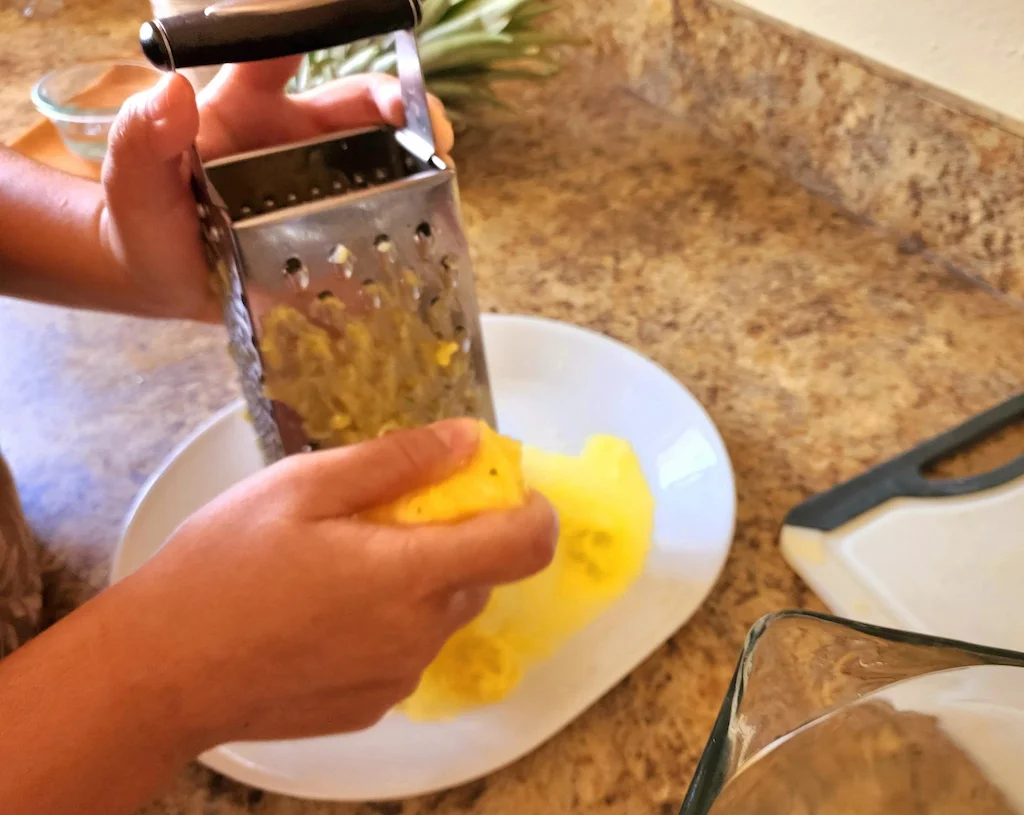 The pineapple being grated onto a plate.