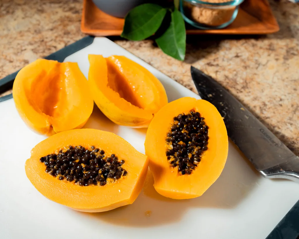 Two ripe, peeled papayas on a cutting board.